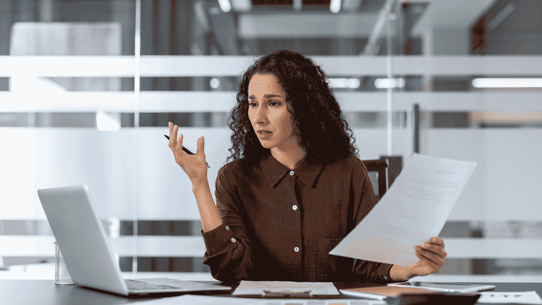 femeie tanara bruneta usor nedumerita uitandu-se in laptop