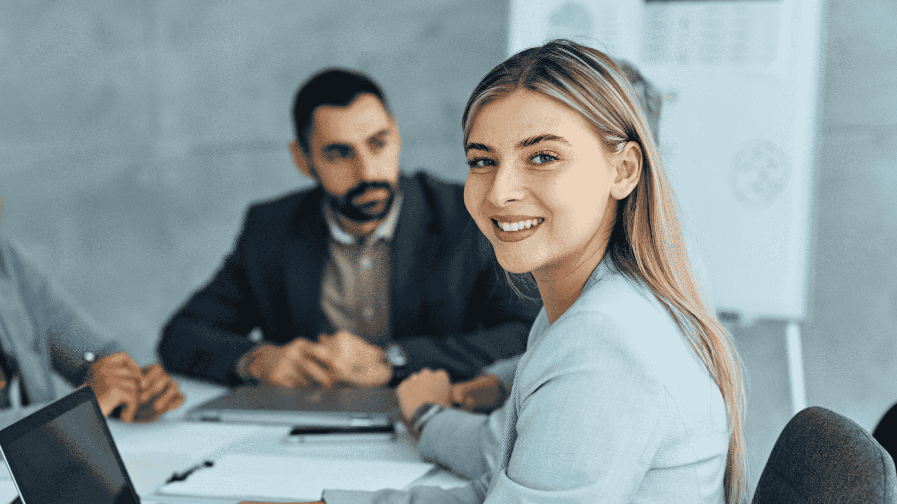 Femeie zambind la camera lucrand intr-un birou